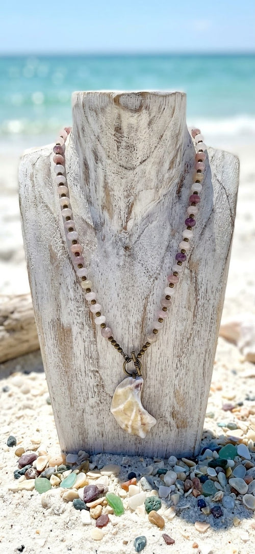 Athena necklace on a whitewashed wooden bust with sea glass and shells on the sand