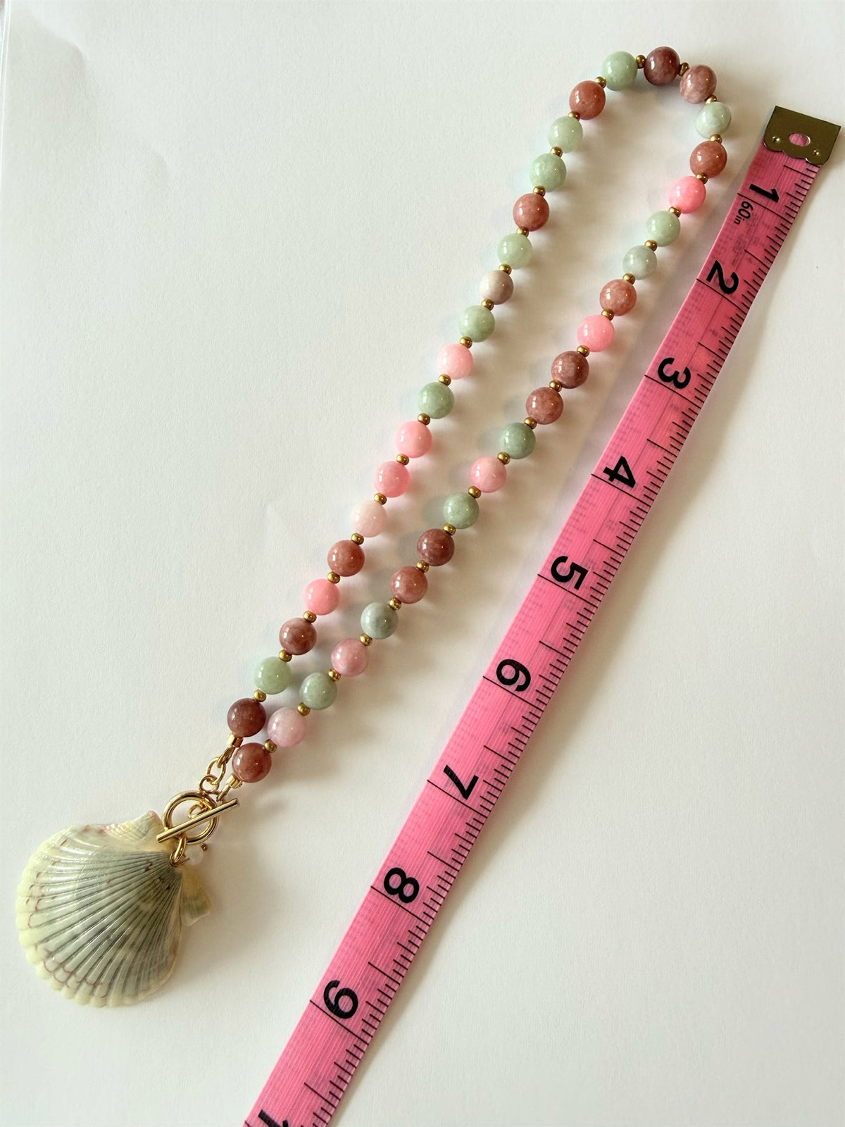 Eos necklace laid flat beside a tape measure showing its 18 inch length