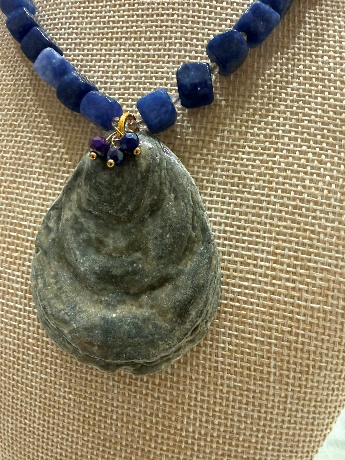 Close-up of the grey oyster shell pendant and gold-wired bead cluster