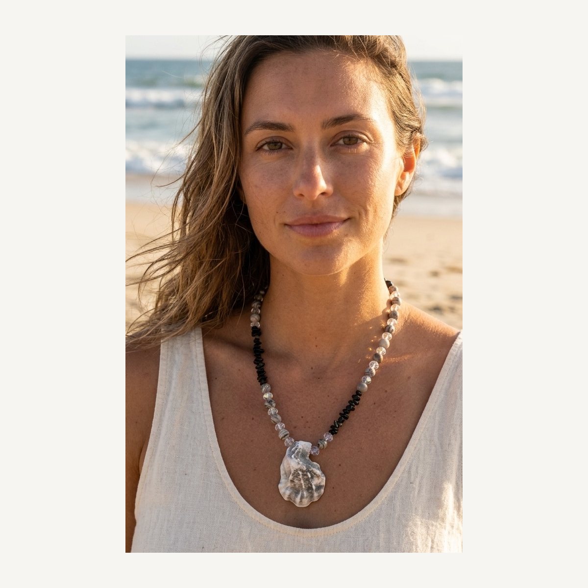 Nyx necklace worn by Jeni on the beach: black labradorite fragments, Picasso jasper, clear glass beads and an oyster shell pendant