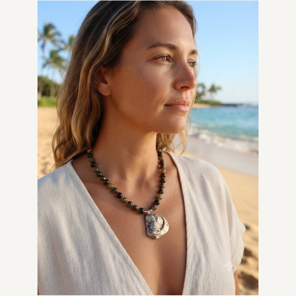 Glauce necklace worn by Jeni on the beach: dark green stone beads with an oyster shell pendant