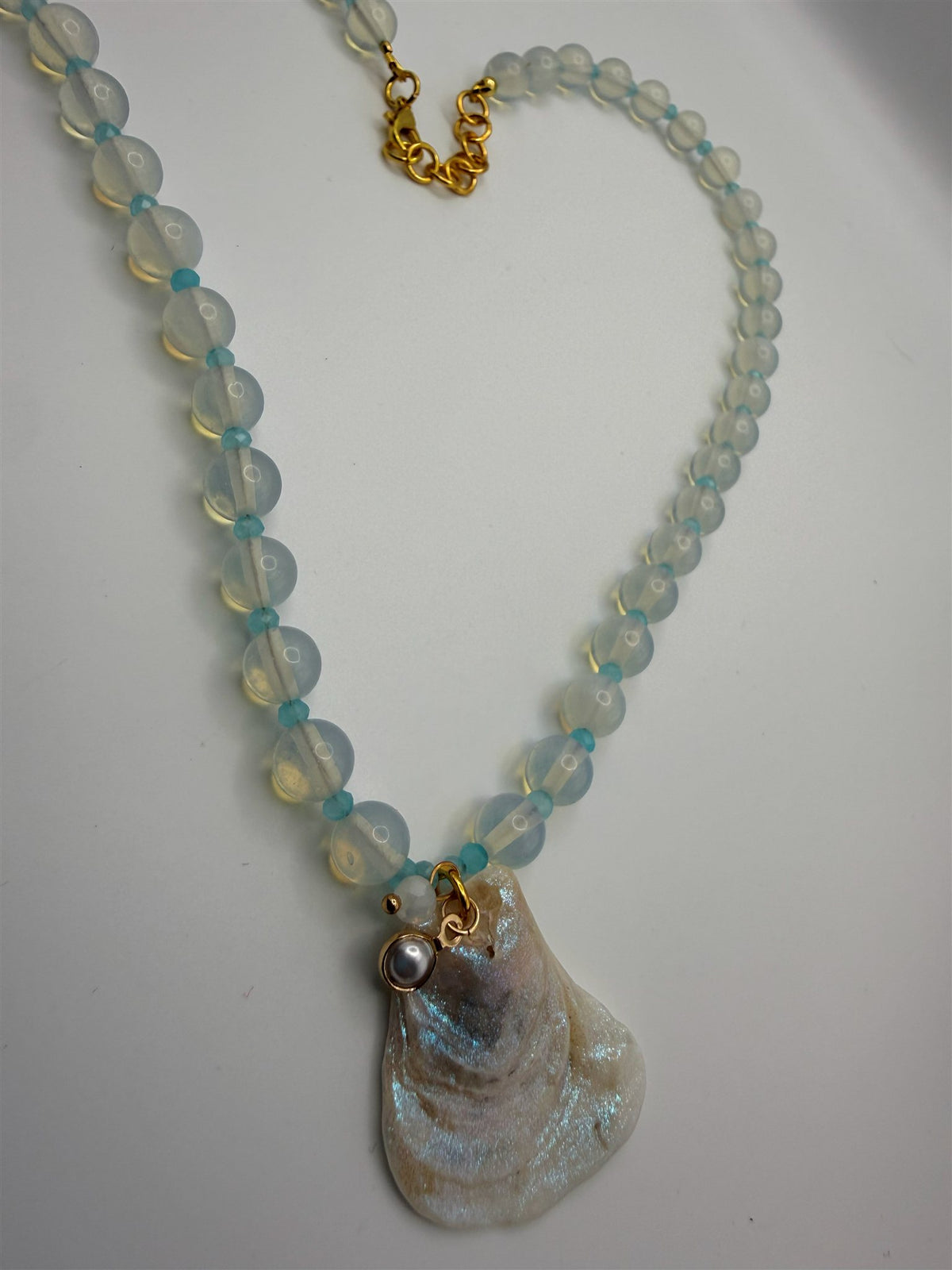 Close-up of the Selene necklace: moonstone beads, aqua faceted glass spacers, pearl charm and iridescent oyster shell